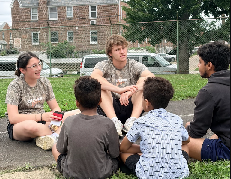 Participants sitting and talking with children outdoors